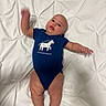 baby, infant, child, lying_down, bed, white_bedding, quilted_blanket, blue_onesie, zebra, shirt, smiling, face, arms, legs, barefoot, indoor, portrait, playful, safari, photography