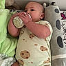 baby, infant, child, bottle, feeding, bed, blanket, stuffed_animal, pillow, onesie, sleeping, lying_down, indoor, cozy, portrait, face, hands, nursery, plush_toy, photography