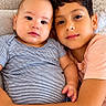 baby, child, siblings, portrait, couch, cuddling, smiling, indoors, home, family, infant, toddler, boy, striped_shirt, pink_shirt, soft_lighting, cushion, close_up, happy, photography