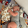 baby, infant, sleeping, bottle_feeding, bed, blanket, stuffed_animals, plush_toys, puppy_toy, monkey_blanket, gray_onesie, indoors, nursery, cozy, lying_down, face, closed_eyes, bedding, portrait, nap_time