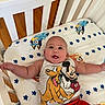 baby, infant, child, smiling, crib, nursery, bedding, cartoon, mickey_mouse, pluto, clothing, red_shorts, white_onesie, lying_down, arms_outstretched, portrait, indoor, wood_floor, happy, playful