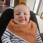 Louison participe au concours pour gagner de l'argent avec cette photo : baby, bib, child, cozy, cute, face, furniture, hand, happy, home, indoor, infant, light, person, seated, skin, smiling, striped_shirt, window, wood