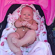 Hazel is registered to the contest to win money with this photo: newborn, baby, infant, child, smiling, stroller, blanket, pink, outdoor, portrait, face, hands, feet, onesie, seated, lying_down, happy, cozy, floral_pattern, photography
