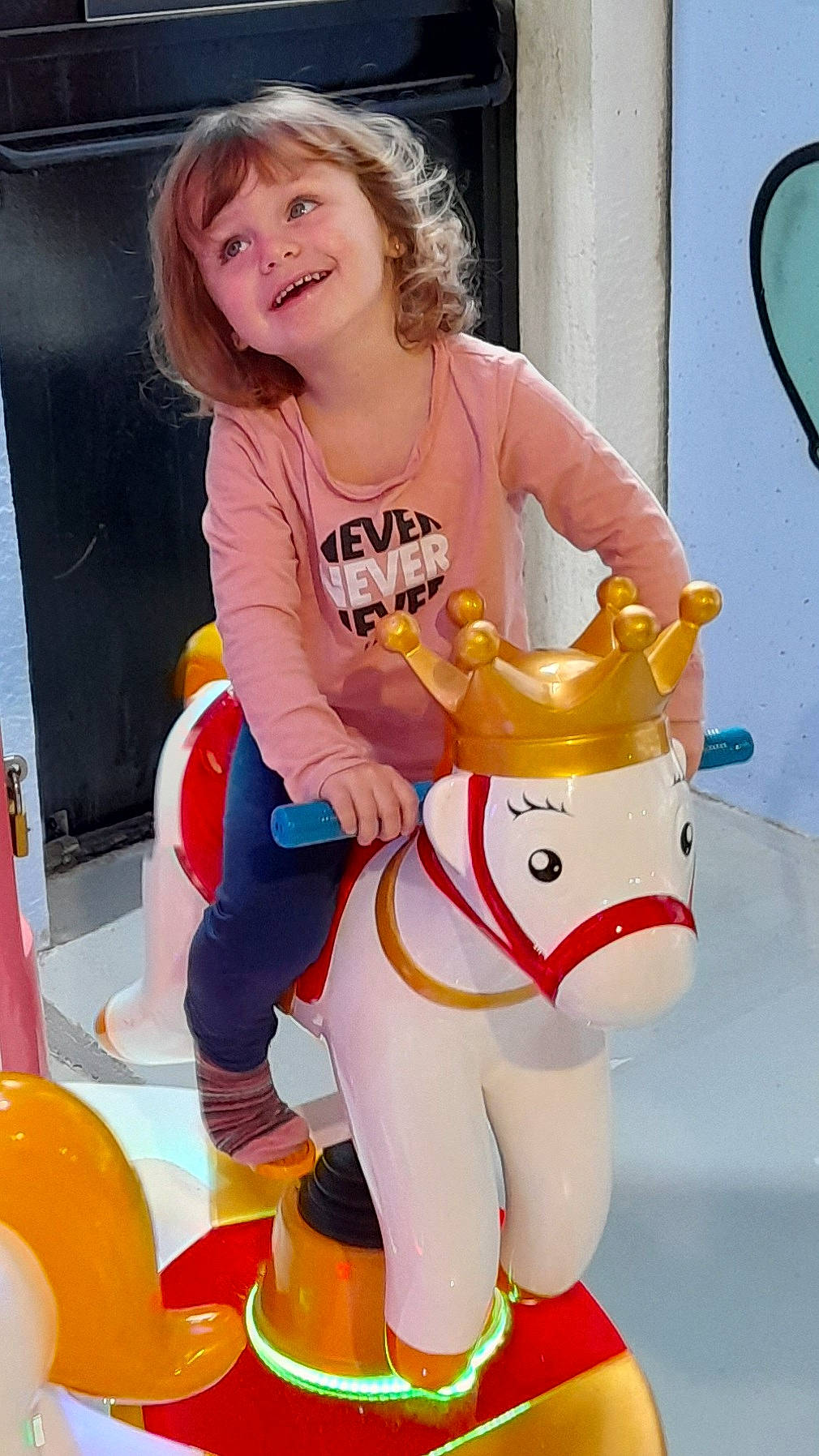 Marie participe au concours pour gagner de l'argent avec cette photo : bridle, carousel, child, event, fun, happy, horse, horse_tack, joy, livestock, orange, party_supply, person, personal_protective_equipment, recreation, riding_toy, smile, toddler, toy, white