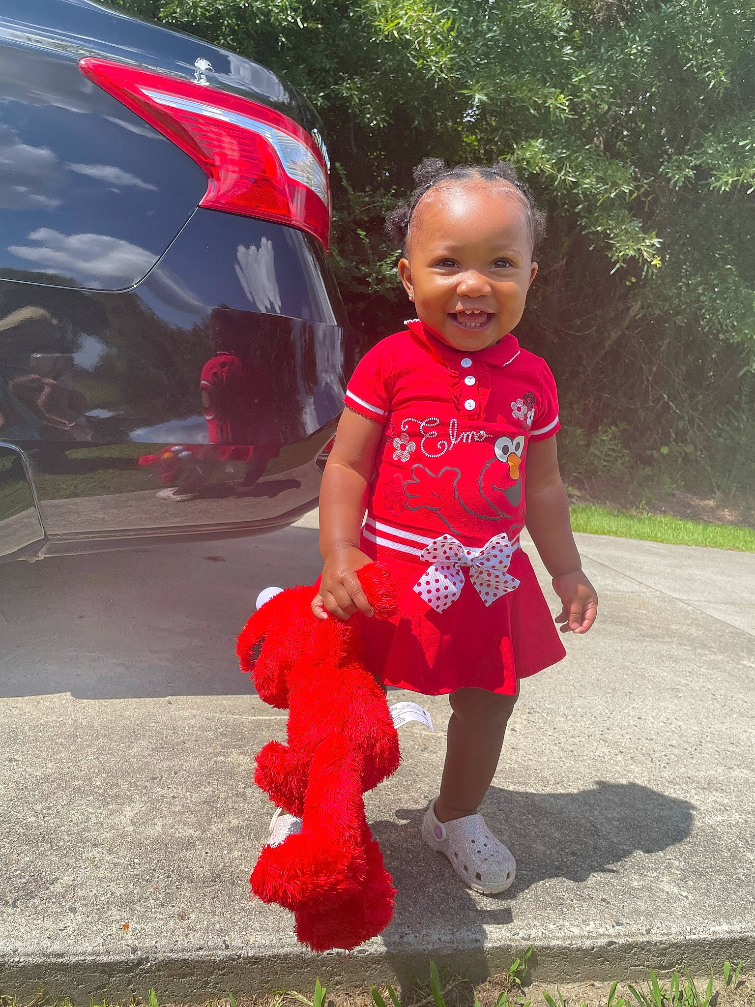 Amani is registered to the contest to win money with this photo: asphalt, automotive_lighting, baby_toddler_clothing, child, electric_blue, fashion_accessory, flag, fun, grass, happy, joy, leisure, magenta, person, pink, recreation, red, smile, toddler, tree