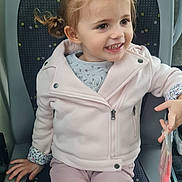 Thaïssya a rejoint le concours — aidez-le/la à gagner de superbes lots ! bus_seat, casual_clothing, child, cute, girl, handbag, happy, holding_object, indoor, jacket, light_pink, pants, patterned_seat, person, pigtails, portrait, seat, smiling, transport, young_child