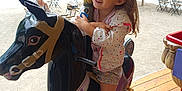 Thaïssya participe au concours pour gagner de l'argent avec cette photo : amusement_ride, carousel, child, daylight, fun, girl, happy, horse, jacket, outdoor, park, people, playground, recreation, shorts, smiling, sneakers, summer_clothing, trees, wooden_floor