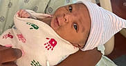 Devonta is registered to the contest to win money with this photo: arm, baby, blanket, closeup, cute, handprints, hat, holding, hospital, hospital_bed, indoors, infant, medical_bracelet, newborn, person, portrait, resting, skin, striped_hat, wrapped