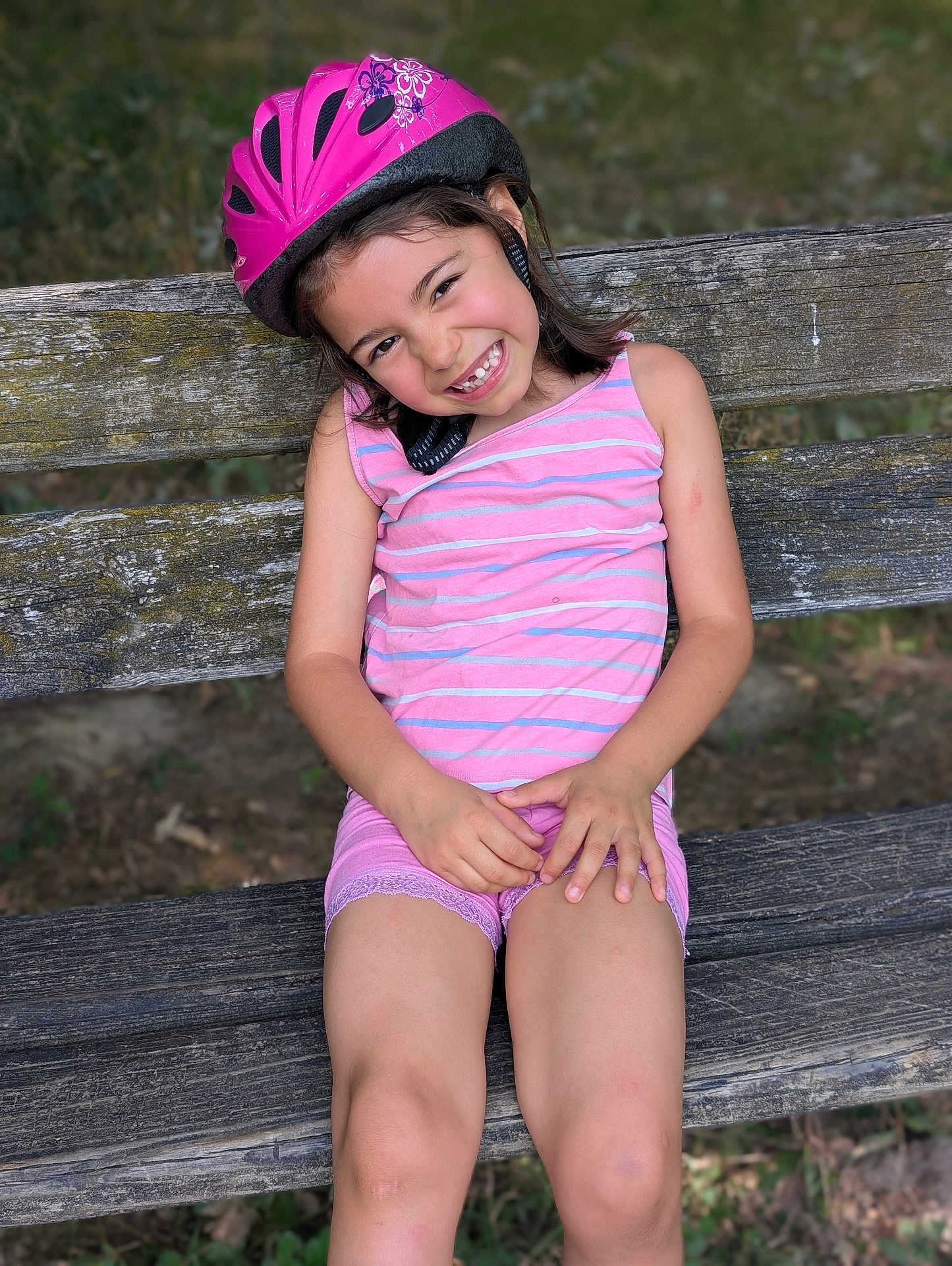 Lorena a rejoint le concours — aidez-le/la à gagner de superbes lots ! bench, casual, child, clothing, daylight, girl, greenery, happy, helmet, nature, outdoor, pink, playful, portrait, shorts, sitting, smiling, summer, tank_top, wood