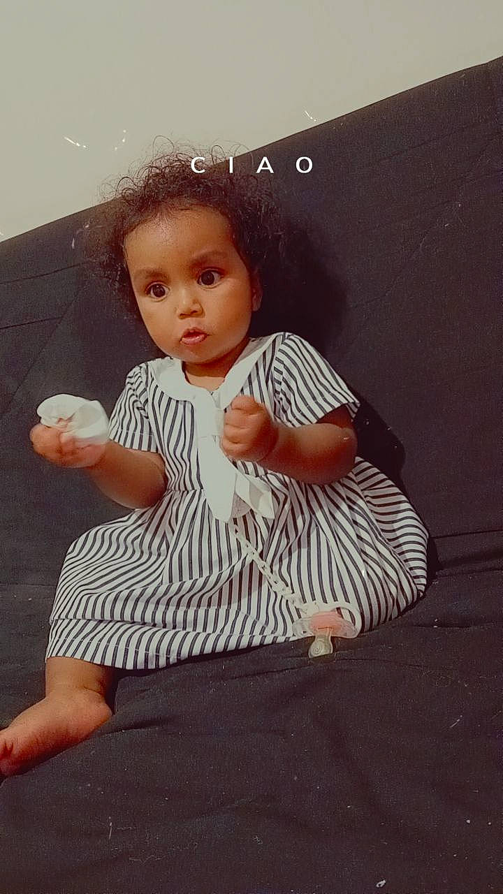 Cataleya participe au concours pour gagner de l'argent avec cette photo : baby_toddler_clothing, cheek, child, day_dress, finger, flash_photography, flooring, foot, gesture, happy, human_body, human_leg, one_piece_garment, pattern, person, sitting, sleeve, surprise, thumb, toddler