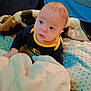 baby, child, blanket, bedroom, batman_shirt, couch, curious, face, indoor, infant, person, pillow, portrait, seated, soft, star_pattern, toddler, wearing_clothes, young_child, cute