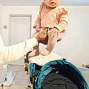 Keya a rejoint le concours — aidez-le/la à gagner de superbes lots ! baby, baby_clothes, blanket, child, clothing, curious, door, floor, furniture, hand, holding, home, indoor, infant, looking, person, pink, stroller, tiled_floor, white