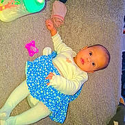 Keya participe au concours pour gagner de l'argent avec cette photo : baby, infant, carpet, bottle, pacifier, baby_wipes, blue_skirt, white_top, tights, face, person, child, lying_down, indoors, cute, clothing, floor, toy, blanket, expression