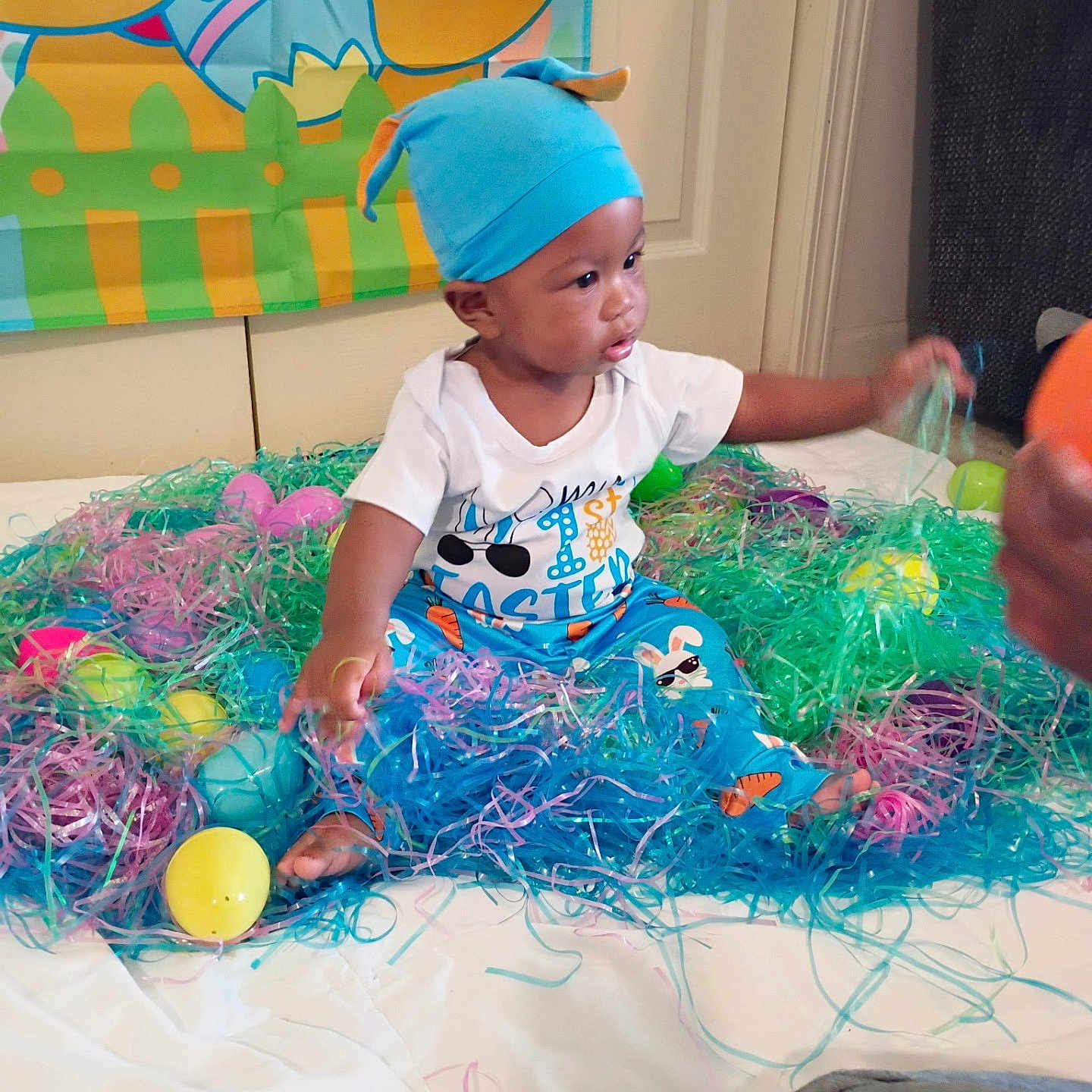 Jaceyon joined the competition — help win amazing prizes! baby, banner, celebration, child, colorful, curious, cute, decorative_grass, easter, festive, floor, hat, holiday, indoor, pajamas, plastic_eggs, playful, portrait, sitting, toy
