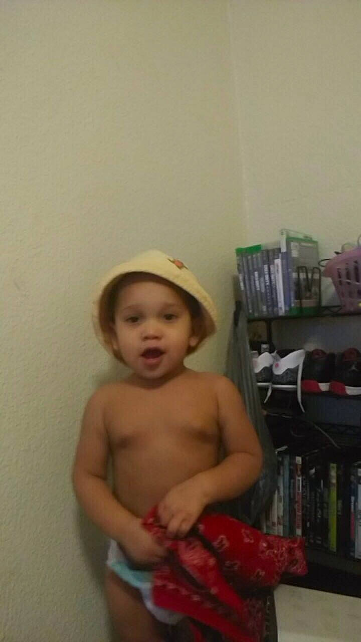 Landyn is registered to the contest to win money with this photo: abdomen, baby, barechested, baseball_cap, bookcase, cap, chest, diaper, elbow, flooring, gesture, human_leg, person, room, shelf, shelving, stomach, thigh, thumb, toddler