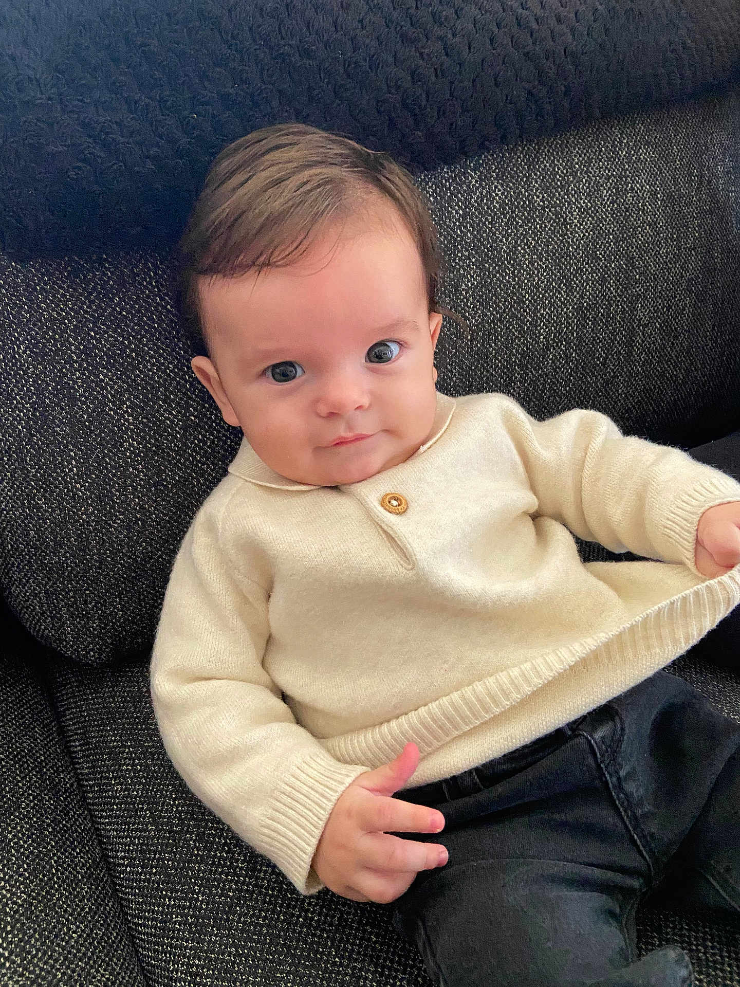 Livio participe au concours pour gagner de l'argent avec cette photo : baby, child, infant, sweater, cream_color, couch, blanket, hand, face, eyes, hair, clothing, portrait, indoor, seated, looking_at_camera, cozy, texture, fabric, casual