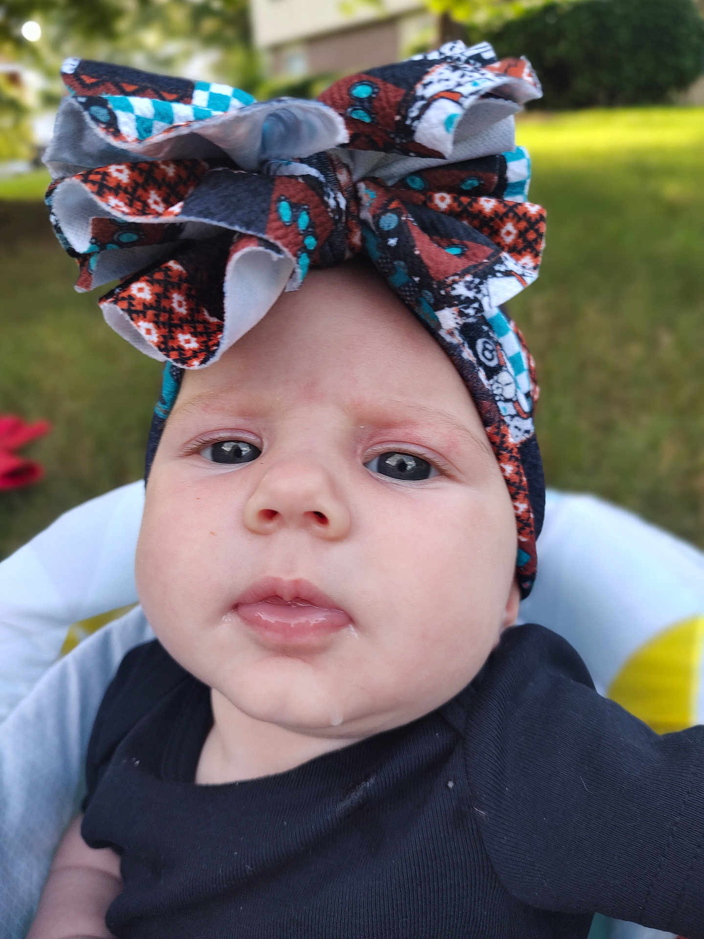 Winifred is registered to the contest to win money with this photo: baby, headband, bow, drool, face, infant, outdoor, closeup, expression, clothing, person, child, skin, headwear, portrait, young, cute, apparel, babyface, background