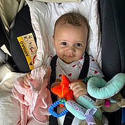 Mallory participe au concours pour gagner de l'argent avec cette photo : baby, car_seat, child, plush_toy, soft_toy, pink_cloth, smile, infant, seatbelt, white_clothing, heart_pattern, indoor, cute, happy, face, human, child_safety, car_interior, toy, comfort