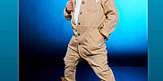 Tymair is registered to the contest to win money with this photo: child, boy, cap, boots, beige_jumpsuit, pose, studio, blue_background, fashion, confident, standing, portrait, cute, casual_clothing, footwear, hat, young, person, model, expression