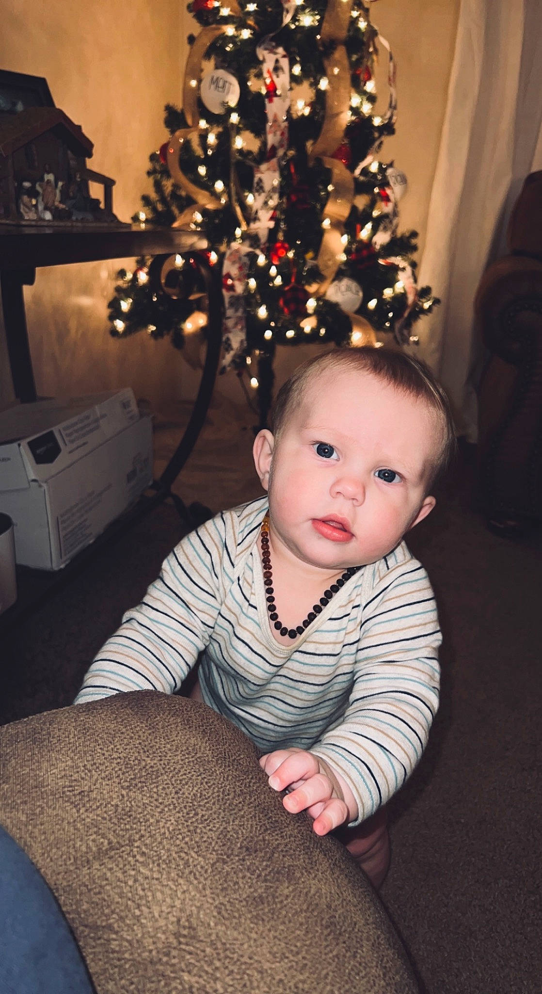 Kash is registered to the contest to win money with this photo: baby, baby_toddler_clothing, christmas, christmas_decoration, christmas_ornament, christmas_tree, event, flash_photography, flooring, happy, head, holiday, human_body, ornament, person, plant, sleeve, standing, toddler, tree