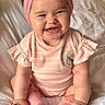 baby, bed, child, chubby_cheeks, closeup, clothing, cute, happy, headwear, indoors, infant, person, pink_dress, pink_headband, pink_socks, portrait, sitting, smiling, white_bedspread, young_child