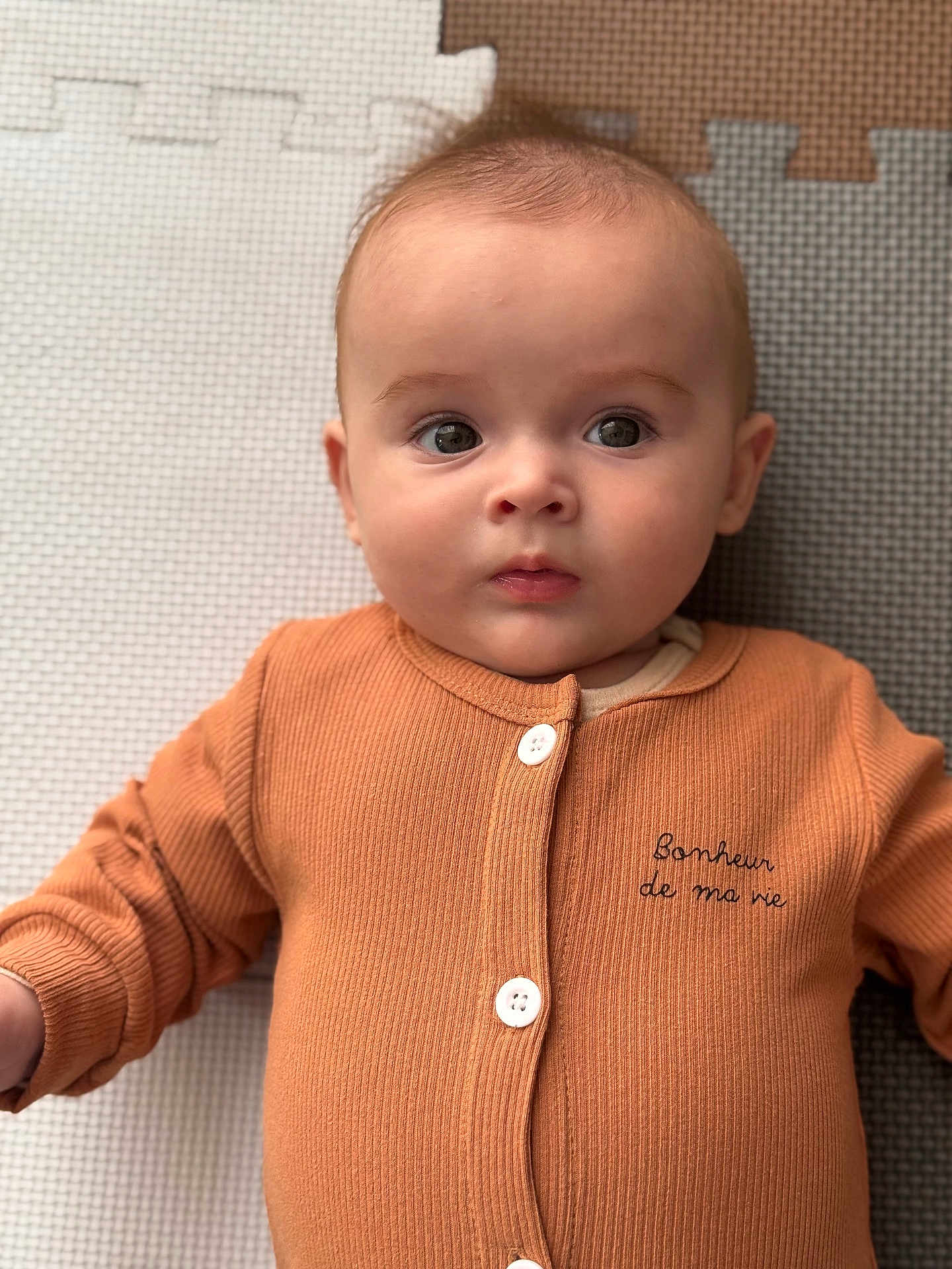 Célestin participe au concours pour gagner de l'argent avec cette photo : baby, infant, child, face, eyes, clothing, buttoned_shirt, orange, play_mat, texture, portrait, lying_down, cute, young_child, skin, expression, indoors, soft_light, close_up, person