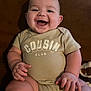 baby, smiling, infant, onesie, clothing, happy, child, cute, sitting, chubby, face, person, indoor, skin, young, joyful, hands, legs, head, couch