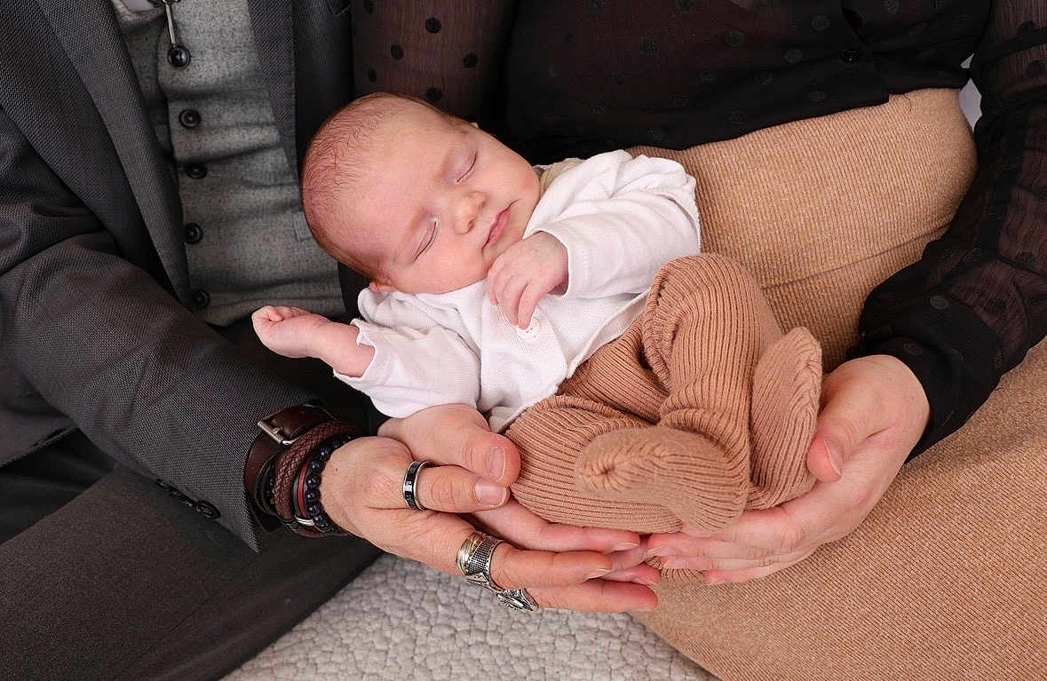 Elena a rejoint le concours — aidez-le/la à gagner de superbes lots ! baby, newborn, sleeping, hands, adult_hands, parent, family, cozy, knit_socks, beige, white_top, cradle, rings, jewelry, suit, gray_suit, polka_dot_blouse, close_up, indoor, portrait