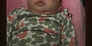 Amoura joined the competition — help win amazing prizes! baby, infant, blanket, onesie, patterned_clothing, pink, face, portrait, indoor, soft_lighting, phone_screen, technology, curious, lying_down, child, young, cute, home, resting, baby_clothes