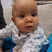 Oscar a rejoint le concours — aidez-le/la à gagner de superbes lots ! baby, child, indoor, couch, pillow, clothing, shirt, music_notes, face, person, sitting, blanket, cozy, expression, cute, young_child, portrait, home, soft, curious