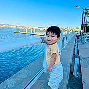 Aria joined the competition — help win amazing prizes! toddler, child, smiling, outdoor, waterfront, railing, blue_sky, casual_clothing, white_shoes, concrete, daylight, happy, person, nature, urban, sidewalk, park, leisure, young_child, standing