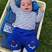 Benoît a rejoint le concours — aidez-le/la à gagner de superbes lots ! baby, infant, smiling, striped_shirt, blue_pants, socks, towel, blanket, container, grass, outdoor, portrait, face, eyes, cheeks, hands, feet, cute, happy, bedding