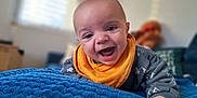 Benoît participe au concours pour gagner de l'argent avec cette photo : apparel, baby, blanket_texture, blue_blanket, child, cozy, crawling, cute, face, furniture, happy, home, indoor, infant, orange_bib, plush_toy, portrait, smiling, soft_light, teddy_bear