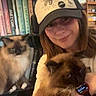 blue_eyes, books, bookshelf, brown_cat, cap, casual, cat, cozy, cute, fluffy_cat, furniture, headwear, holding, home, indoor, person, pet, sitting, smile, watch