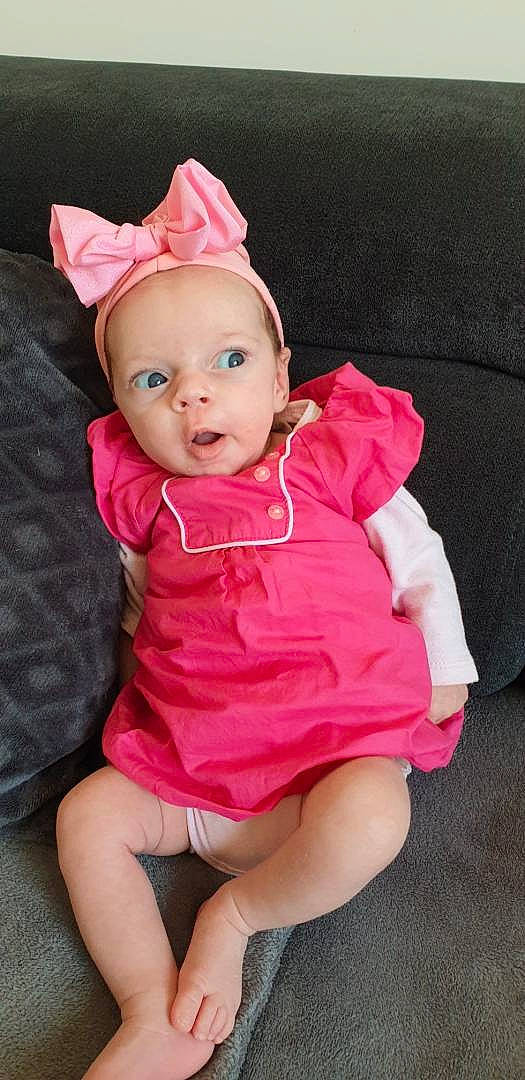 Julia participe au concours pour gagner de l'argent avec cette photo : baby, baby_toddler_clothing, cap, cheek, child, costume_hat, dress, eye, finger, happy, head, headgear, human_body, magenta, person, pink, purple, skin, sleeve, textile