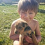 child, puppy, grass, outdoor, sunlight, smile, bare_chest, young, dog, animal, nature, garden, fence, shed, summer, happy, pet, cute, playing, boy