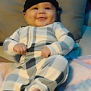 Lamont joined the competition — help win amazing prizes! baby, smiling, infant, beanie, checkered_onesie, couch, cushion, blanket, indoor, happy, chubby_cheeks, person, portrait, cute, relaxed, cozy, soft_fabric, child, seated, home