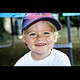 child, smiling, blue_eyes, cap, hat, white_shirt, outdoor, daylight, portrait, happy, blond_hair, young_child, face, cute, person, nature, background_blur, sunny, headwear, casual