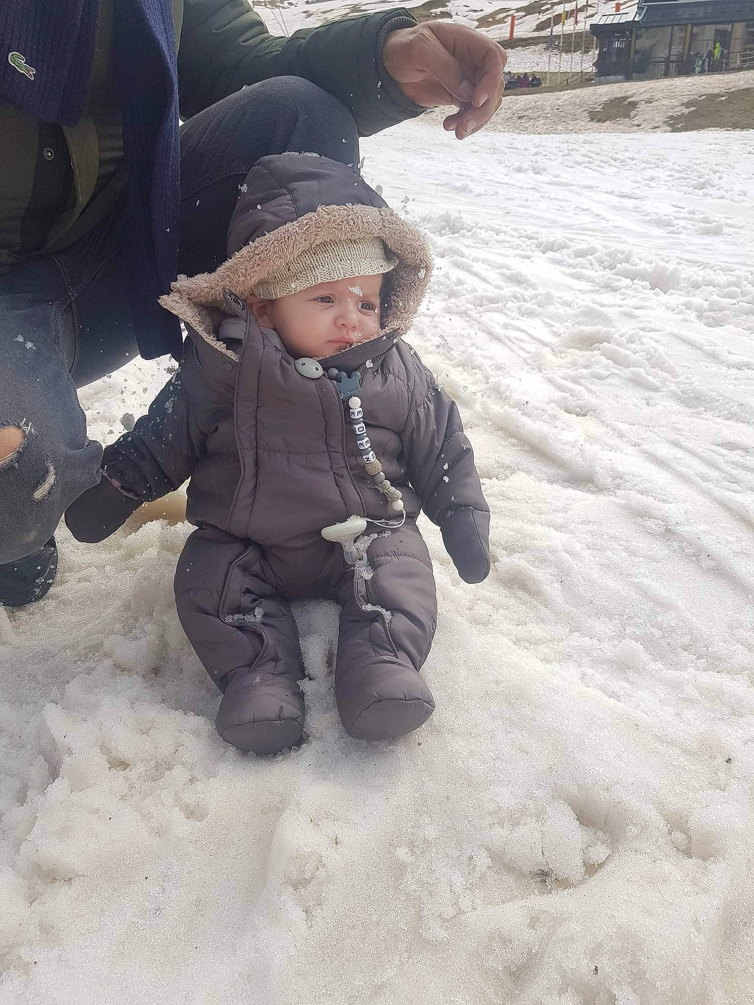 Eden a rejoint le concours — aidez-le/la à gagner de superbes lots ! automotive_tire, baby, baby_toddler_clothing, boot, child, family_car, freezing, fun, gesture, glove, hat, headwear, jacket, person, play, recreation, sitting, snow, toddler, vacation