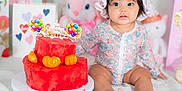 Astoria is registered to the contest to win money with this photo: baby, child, birthday_cake, watermelon_cake, fruit, party, hat, floral_clothing, sitting, cute, celebration, indoor, toy, stuffed_animal, colorful, food, table, white_blanket, decorations, happy_birthday