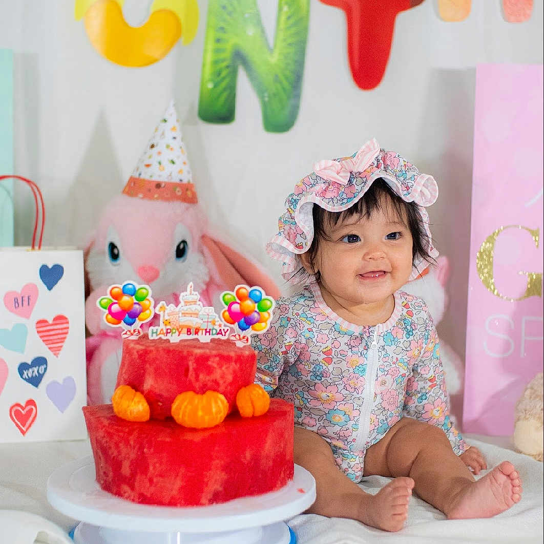 Astoria is registered to the contest to win money with this photo: baby, birthday, bonnet, bunny, cake, celebration, child, colorful, cute, decorations, fruit, happy, indoor, onesie, orange, party, smiling, stuffed_animal, tangerine, watermelon