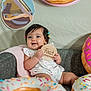 baby, infant, cute, smiling, hair_clips, wooden_sign, four_months, couch, blanket, donut_decoration, colorful, sitting, indoors, happy, child, portrait, celebration, playful, home, decor