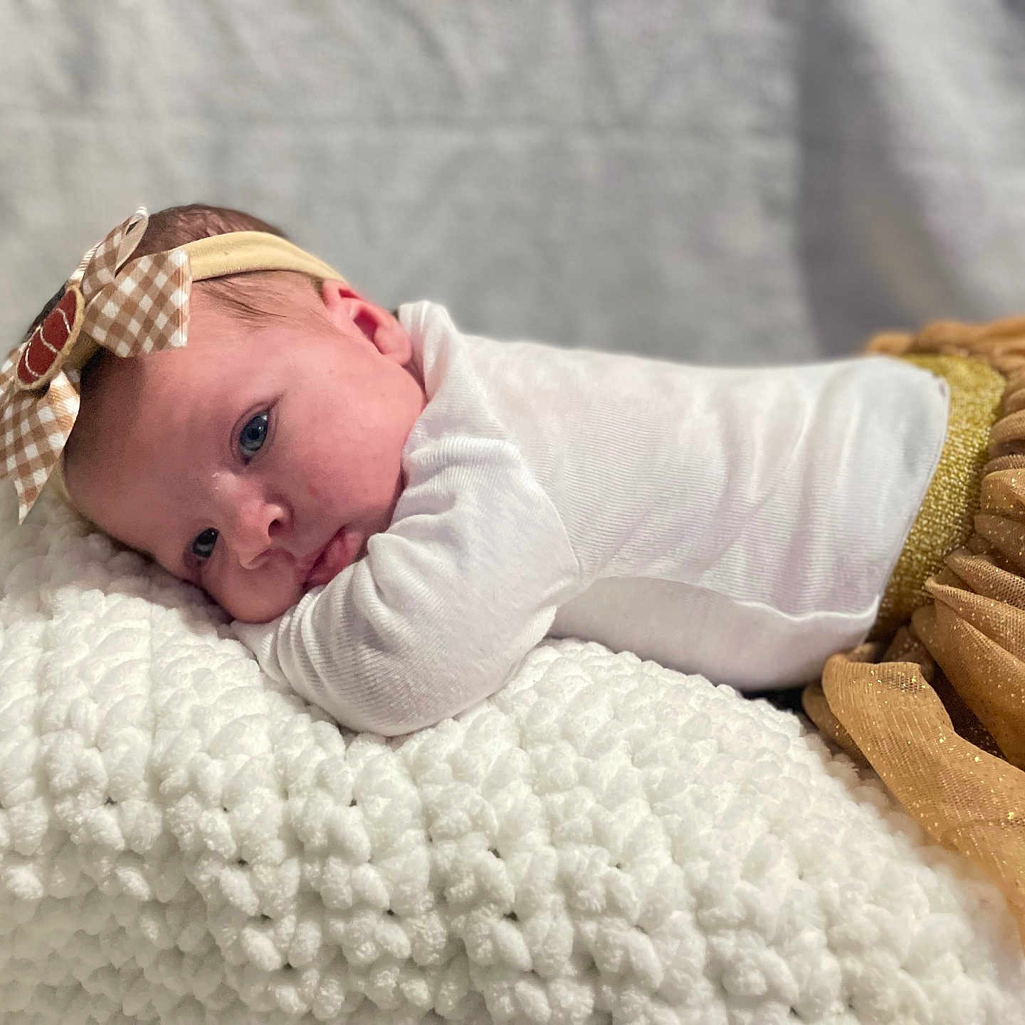 Layla joined the competition — help win amazing prizes! baby, blanket, bow, closeup, clothing, cozy, cute, face, golden_skirt, headband, indoors, infant, newborn, person, portrait, resting, soft_lighting, soft_texture, toddler, white