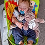 baby, sleeping, pacifier, stuffed_animal, toy, baby_rocker, colorful, lion, monkey, clothing, carpet, foot, hand, cute, infant, child, resting, indoor, soft_toy, peaceful