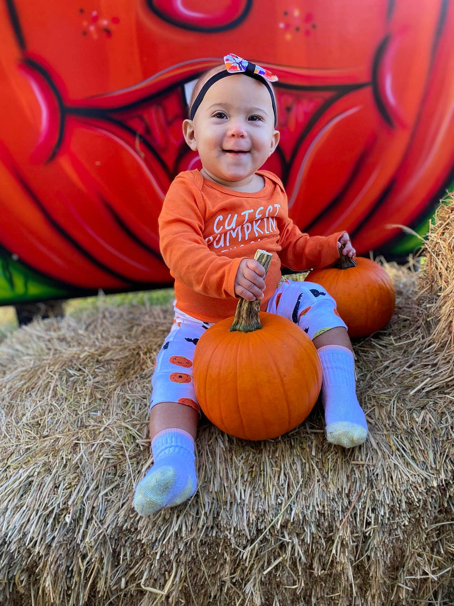 Milana is registered to the contest to win money with this photo: arm, calabaza, cucurbita, eye, face, facial_expression, gourd, grass, happy, head, headwear, joy, leaf, leg, orange, people_in_nature, person, plant, pumpkin, smile