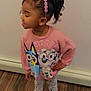 Iliyah is registered to the contest to win money with this photo: child, girl, pajamas, pink, crocs, hair_accessory, sweatshirt, cartoon, standing, wooden_floor, indoor, smiling, cute, closed_eyes, playful, clothing, person, headband, floor, wall