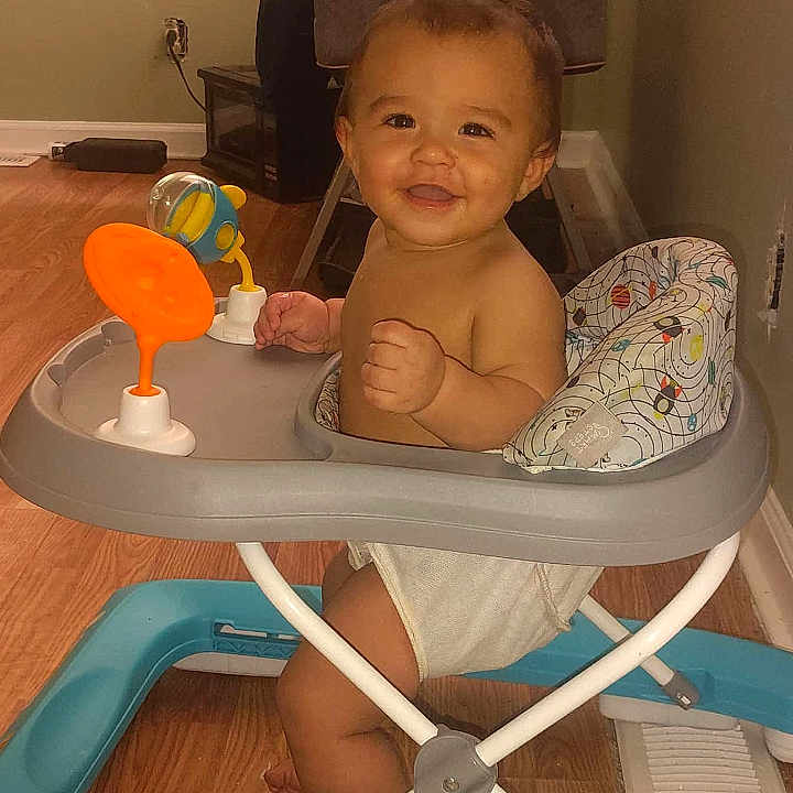 Juan is registered to the contest to win money with this photo: baby, walker, smiling, indoor, toy, floor, wooden_floor, child, happy, sitting, diaper, furniture, vent, person, face, cute, home, infant, young_child, play