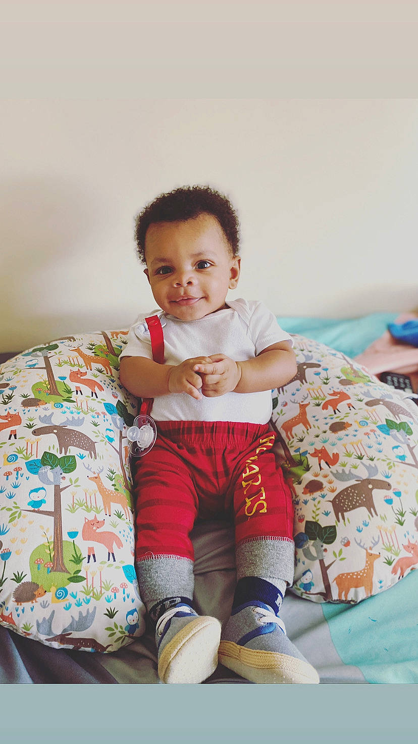 Marc is registered to the contest to win money with this photo: baby, baby_toddler_clothing, comfort, event, facial_expression, hairstyle, happy, human_leg, joy, knee, leisure, pattern, person, shorts, shoulder, skin, sleeve, smile, sock, t_shirt