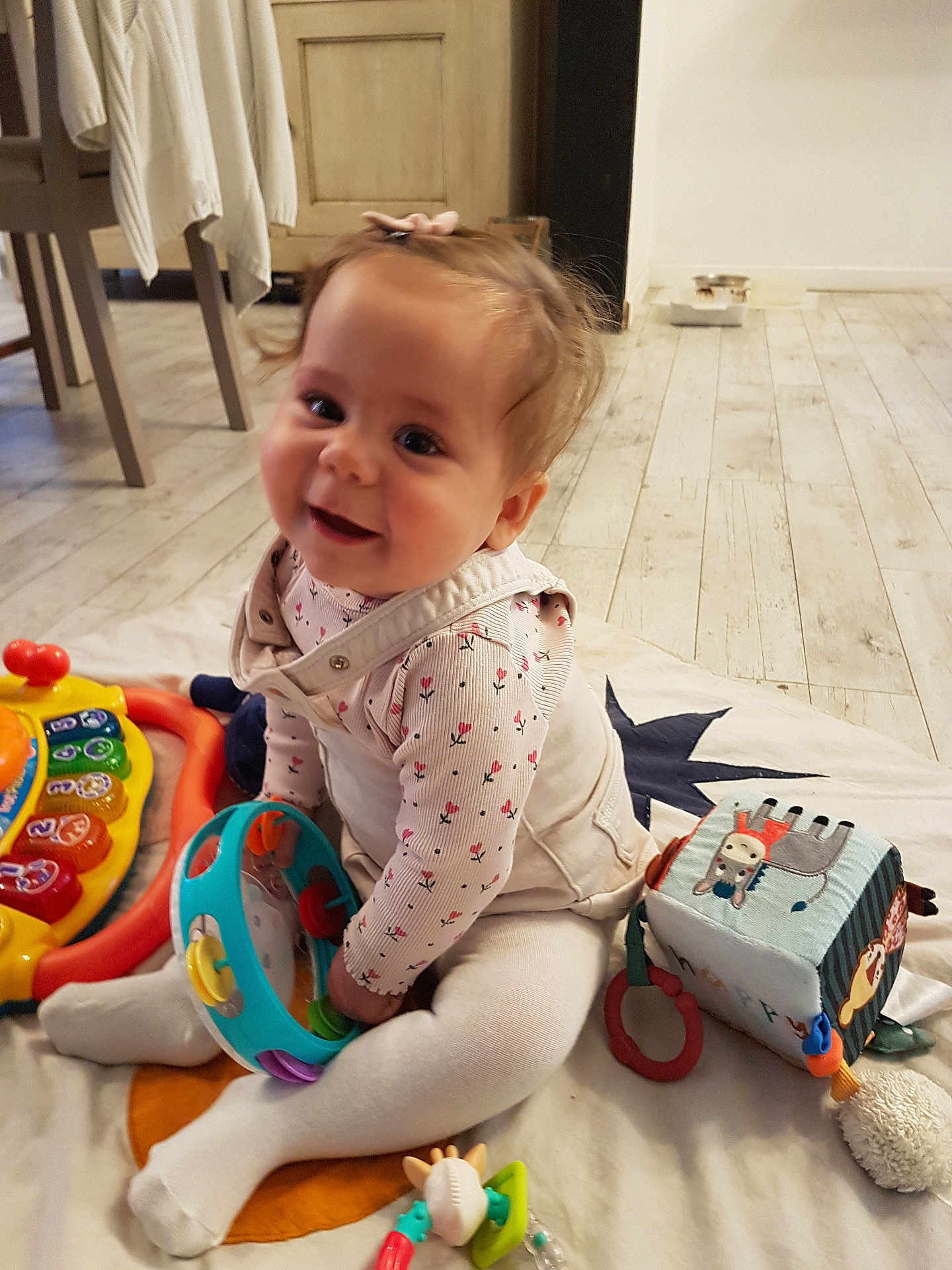 Alice a rejoint le concours — aidez-le/la à gagner de superbes lots ! baby, child, toddler, toy, tambourine, playmat, flooring, indoor, smiling, happy, clothing, sitting, furniture, wooden_floor, soft_toy, cube, girl, bow, cute, colorful