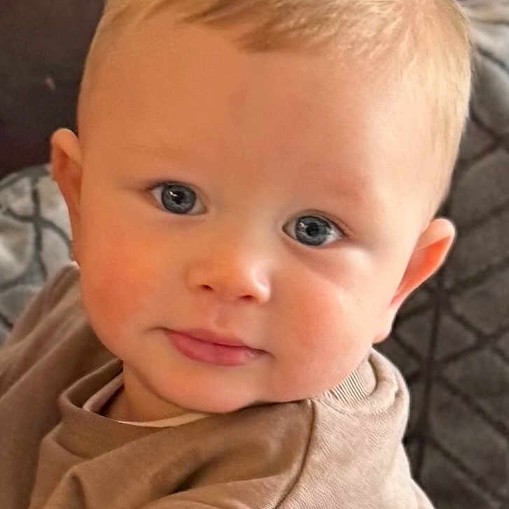 Taylan is registered to the contest to win money with this photo: baby, blonde, clothing, coat, couch, face, furniture, hair, happy, head, jacket, knitwear, newborn, pants, person, photography, portrait, shirt, smile, sweater